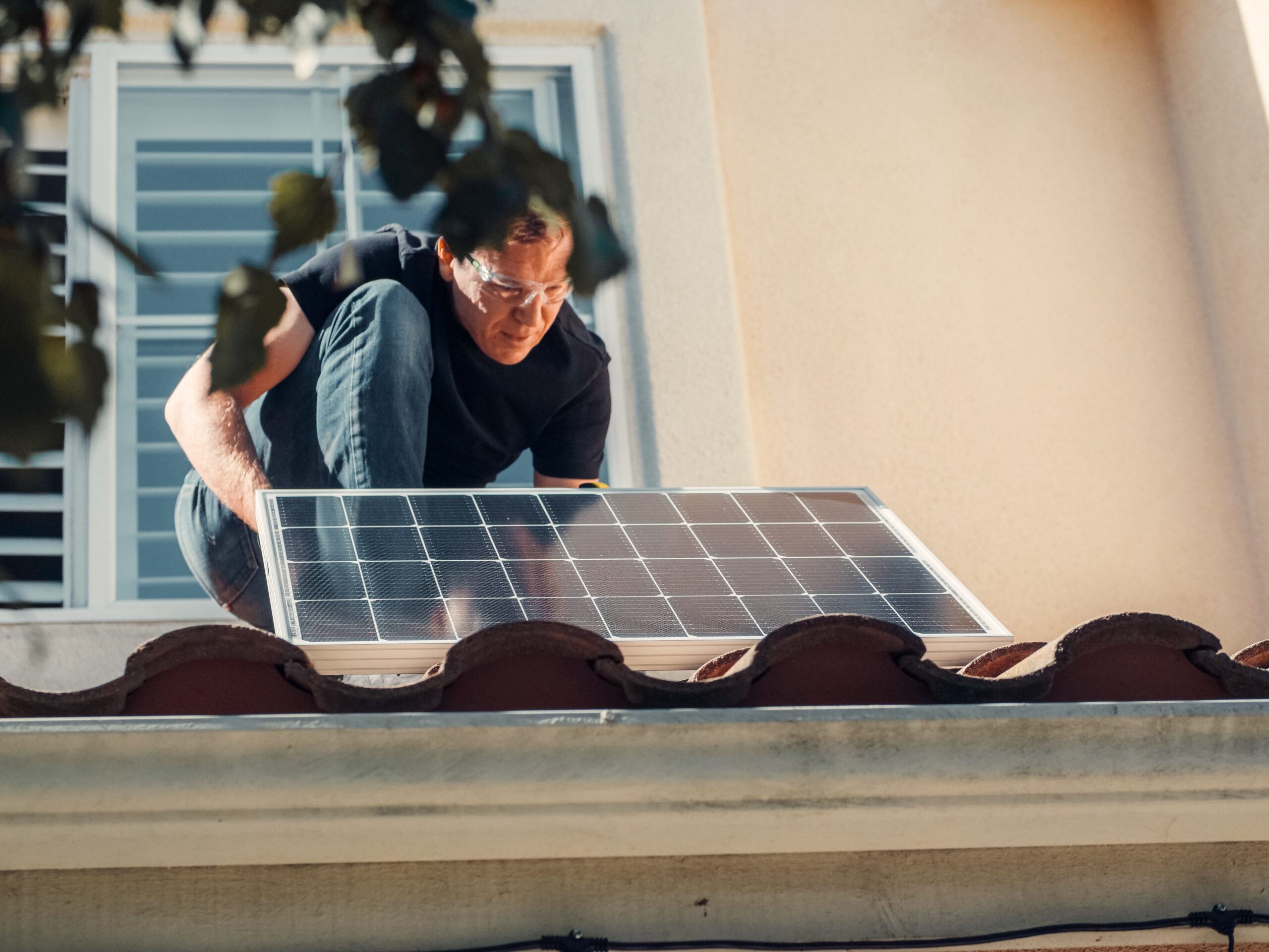 A man replacing a solar panel on the house roof.